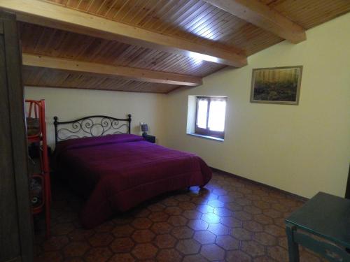 a bedroom with a bed with a purple bedspread and a window at Agriturismo Fonte Magria in Abbadia San Salvatore