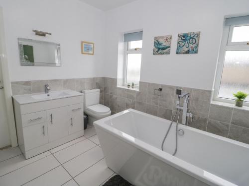 a bathroom with a tub and a toilet and a sink at Bay Lodge in Amlwch