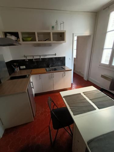 une cuisine avec un évier et une table avec des chaises dans l'établissement T2-Avignon - centre historique, à Avignon