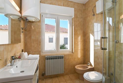 ein Bad mit einem Waschbecken, einem WC und einem Fenster in der Unterkunft Holiday house Vukman in Trogir