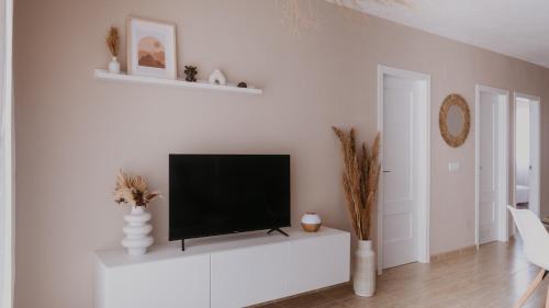 ein Wohnzimmer mit einem Flachbild-TV an einer weißen Wand in der Unterkunft Casa Mahalo - Modern Apartment with Pool, Minutes from Spectacular Beaches in Parque Holandes