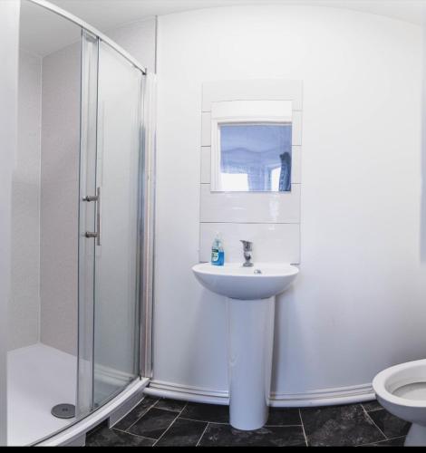 a white bathroom with a sink and a shower at Howard House in Southampton