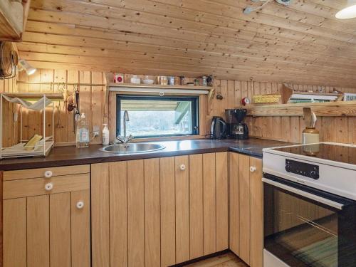 eine Küche mit Holzschränken, einer Spüle und einem Herd in der Unterkunft 4 person holiday home in Martofte in Martofte