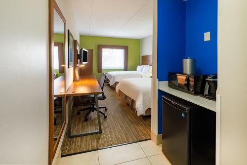 a hotel room with a bed and a desk and a kitchen at Holiday Inn Express Vermilion by IHG in Vermilion