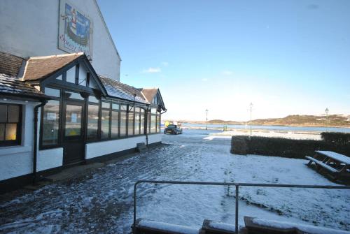 a snow covered street in front of a building at Saucy Mary's Hostel in Kyleakin