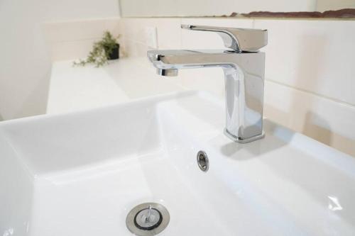 a white bathroom sink with a chrome faucet at ViQi Two bedroom apartment front of century walk Including Premium NETFLIX & Prime AMAZON with 75 INCH TV in Glen Waverley
