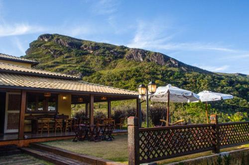 a house with tables and an umbrella and a mountain at Recanto Serra do Trovão in Ouro Preto