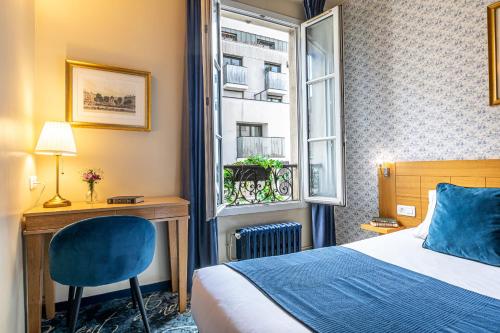 ein Schlafzimmer mit Bett, Schreibtisch und Fenster in der Unterkunft Hotel Romance Malesherbes by Patrick Hayat in Paris