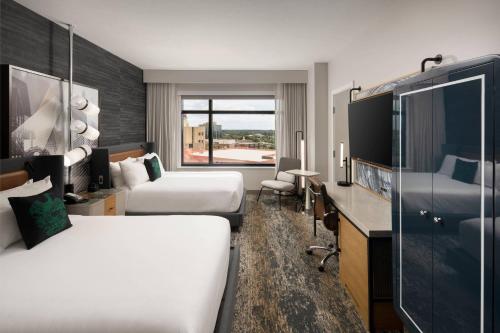 a hotel room with two beds and a television at Luminary Hotel & Co., Autograph Collection in Fort Myers
