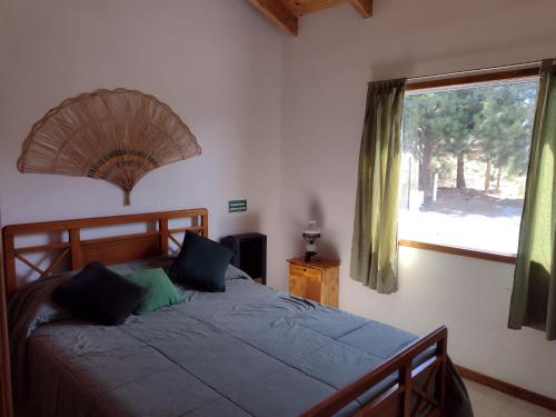Schlafzimmer mit einem großen Bett und einem Fenster in der Unterkunft Cabañas Shehuen Aike Lugar encantador con sol y tranquilidad in Dina Huapi