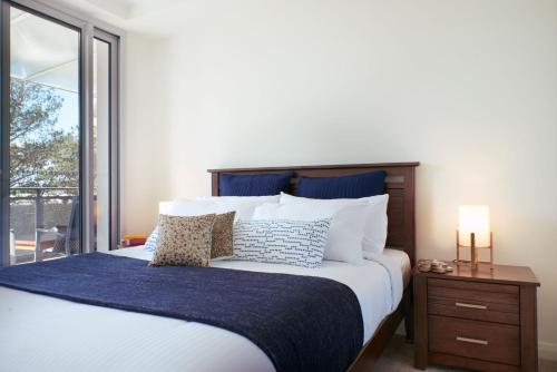 a bedroom with a large bed with a blue blanket at Tranquility the Beach in Huskisson