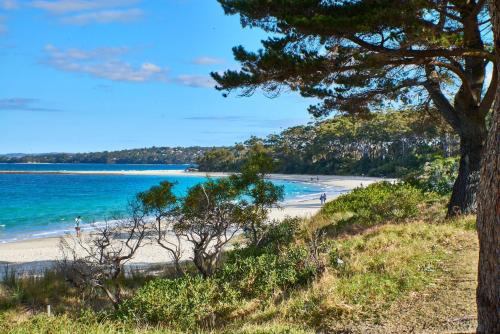 a beach with people on the sand and the ocean at Tranquility the Beach in Huskisson