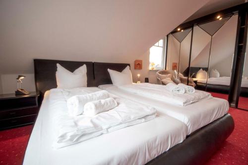 een slaapkamer met 2 bedden met witte lakens en spiegels bij Ferienhaus-Haus-Eversand in Cuxhaven