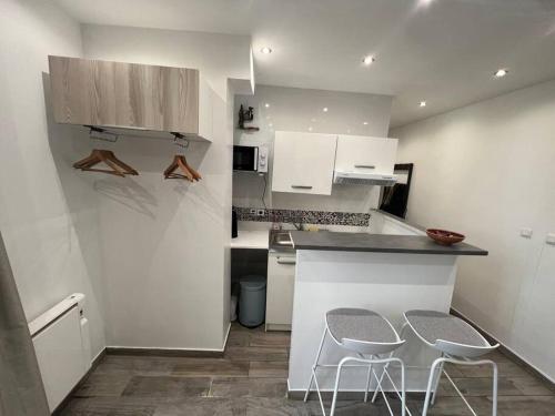 - une cuisine avec des placards blancs et 2 tabourets dans l'établissement Quiet & bright studio 15min away from Paris, à Bondy