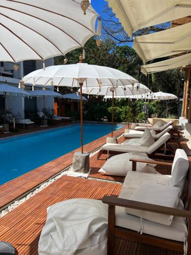 a row of lounge chairs and umbrellas next to a swimming pool at Ride On Beach House in Nosara