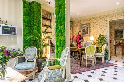 a woman standing in a room with a table and chairs at Romance Malesherbes by Patrick Hayat in Paris