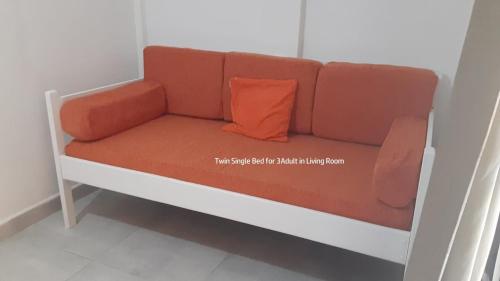 a brown couch with an orange pillow on it at Beach Club Condos at Popeyes in Caye Caulker