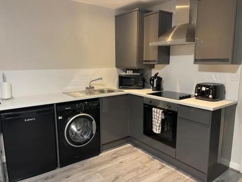 a kitchen with a sink and a washing machine at Hosted By Ryan - 2 Bedroom Apartment in Liverpool
