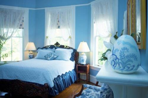 a bedroom with a bed with blue walls and windows at Lookaway Inn in North Augusta
