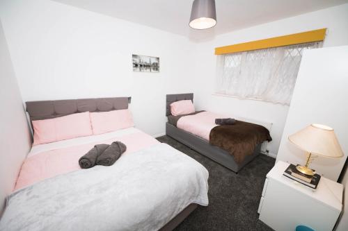 #Gorgeous 3 beds home#7min to subway, free parking في Thamesmead: غرفة نوم بسريرين وطاولة بها مصباح