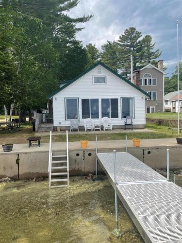 a white house with a dock in the water at CAMP CARROLL LIMIT 6 home in North Sebago