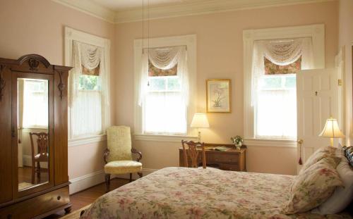 a bedroom with a bed and a chair and windows at Lookaway Inn in North Augusta