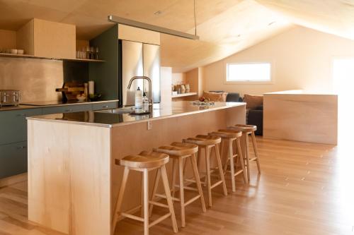 a kitchen with a counter and bar stools at Petit hôtel de la Montagne in Havre-Aubert