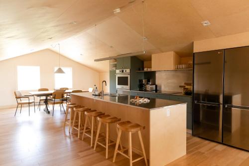 a kitchen with a bar with stools and a table at Petit hôtel de la Montagne in Havre-Aubert