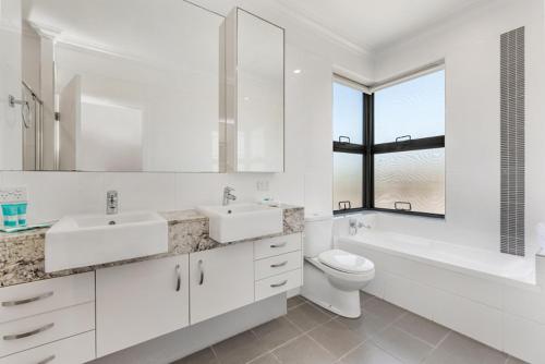 a white bathroom with two sinks and a toilet at Sand Dunes Resort Accommodation in Marcoola