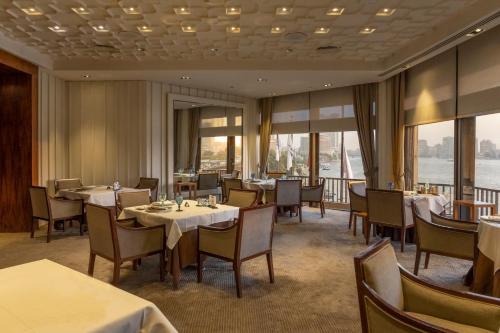 a dining room with tables and chairs and windows at InterContinental Cairo Semiramis by IHG in Cairo