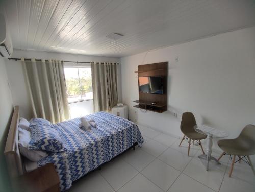 a bedroom with a bed and a tv and a window at Pousada Marihá in Piranhas