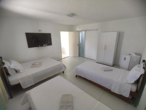 a hotel room with two beds and a flat screen tv at Pousada Marihá in Piranhas