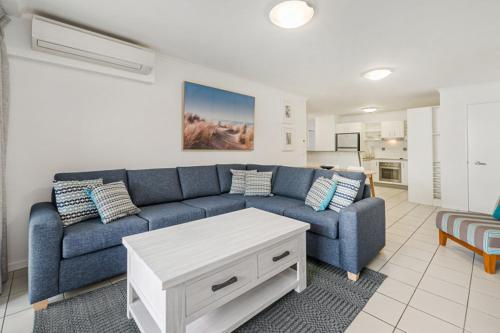 a living room with a blue couch and a table at Sand Dunes Resort Accommodation in Marcoola