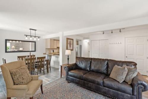 a living room with a leather couch and a kitchen at Mountainside Cozy Walk to Gondola Hot Tub Condo in Steamboat Springs
