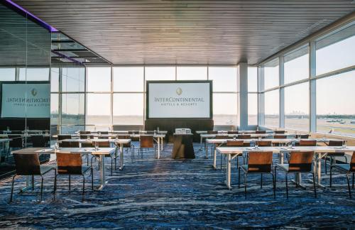 a conference room with tables and chairs and a screen at InterContinental Minneapolis - St. Paul Airport by IHG in Minneapolis
