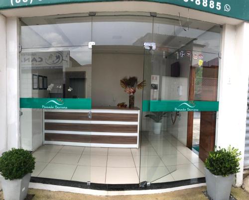 una tienda frente con una puerta de cristal y dos plantas en Pousada Serrana en Ubajara