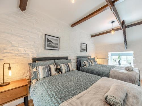 a bedroom with two beds and a wooden desk at Old Stables Cottage in Blaenporth