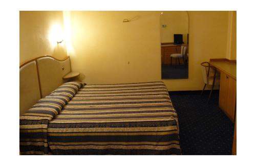 a bed in a hotel room with a striped blanket on it at Albergo Milano in Boario Terme