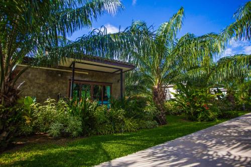 a house with palm trees in front of a yard at Palm Pran Resort in Pran Buri