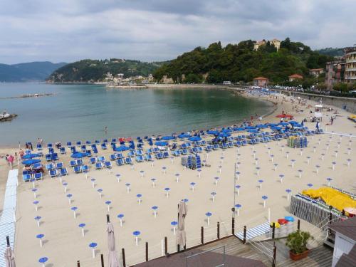 a beach with blue and white umbrellas and chairs at Affittacamere La Baia Di Lerici in Lerici
