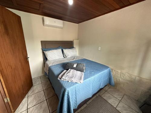 Un dormitorio con una cama azul con una toalla. en Recanto Pé na Areia SC en Palhoça