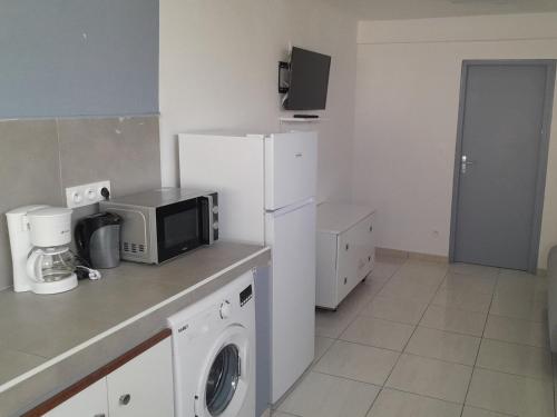 uma cozinha com um frigorífico branco e um micro-ondas em Cosy cannelle em Caiena