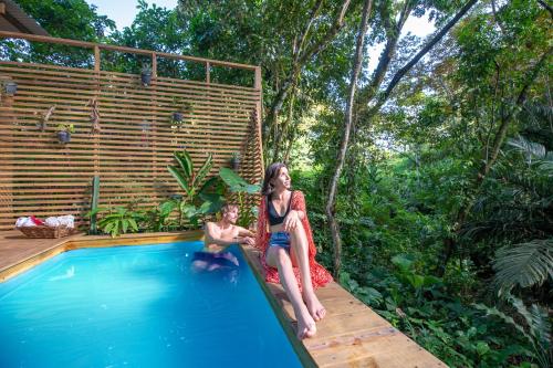 a woman and a child sitting on the side of a swimming pool at Monkey Tiny House - Private swimming pool in Big Bight