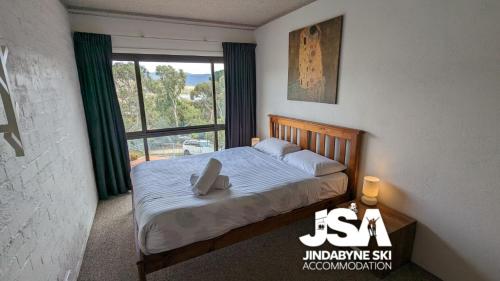- une chambre avec un lit et une grande fenêtre dans l'établissement Mountain View Kirwan 47, à Jindabyne