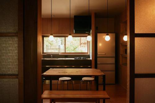 a kitchen with a wooden table and two stools at 目の前が吉野川・雨天でも屋外体験ができる絶景の一軒家 in Ōtakuchi