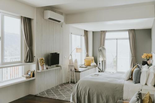 1 dormitorio con 1 cama, TV y ventanas en Sunrise Yunqi Teahouse en Alishan