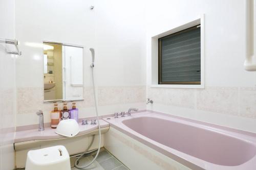 a white bathroom with a tub and a window at 目の前が吉野川・雨天でも屋外体験ができる絶景の一軒家 in Ōtakuchi