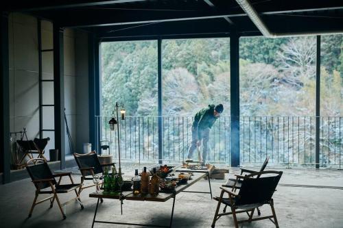 a man standing in a room with a table and chairs at 目の前が吉野川・雨天でも屋外体験ができる絶景の一軒家 in Ōtakuchi
