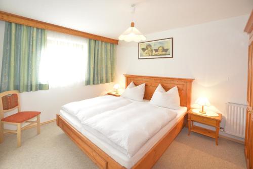 Schlafzimmer mit einem Bett mit weißer Bettwäsche und einem Fenster in der Unterkunft Fernblick in Leutasch