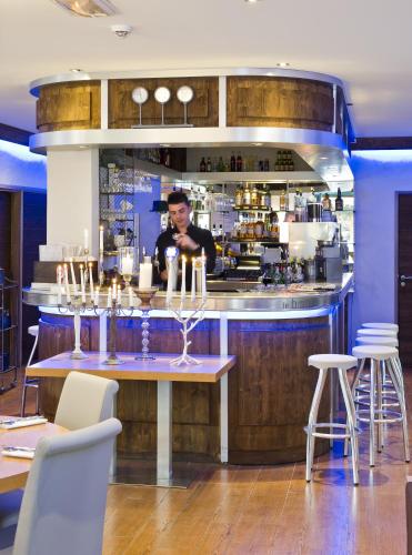 a man standing behind a bar in a restaurant at Hotel Christiania in La Clusaz